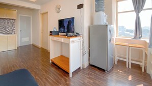 A compact living space with a kitchenette, a TV, a water dispenser, and a window with curtains. - Spacious 1Br At Jarrdin Cihampelas Apartment (Bandung)