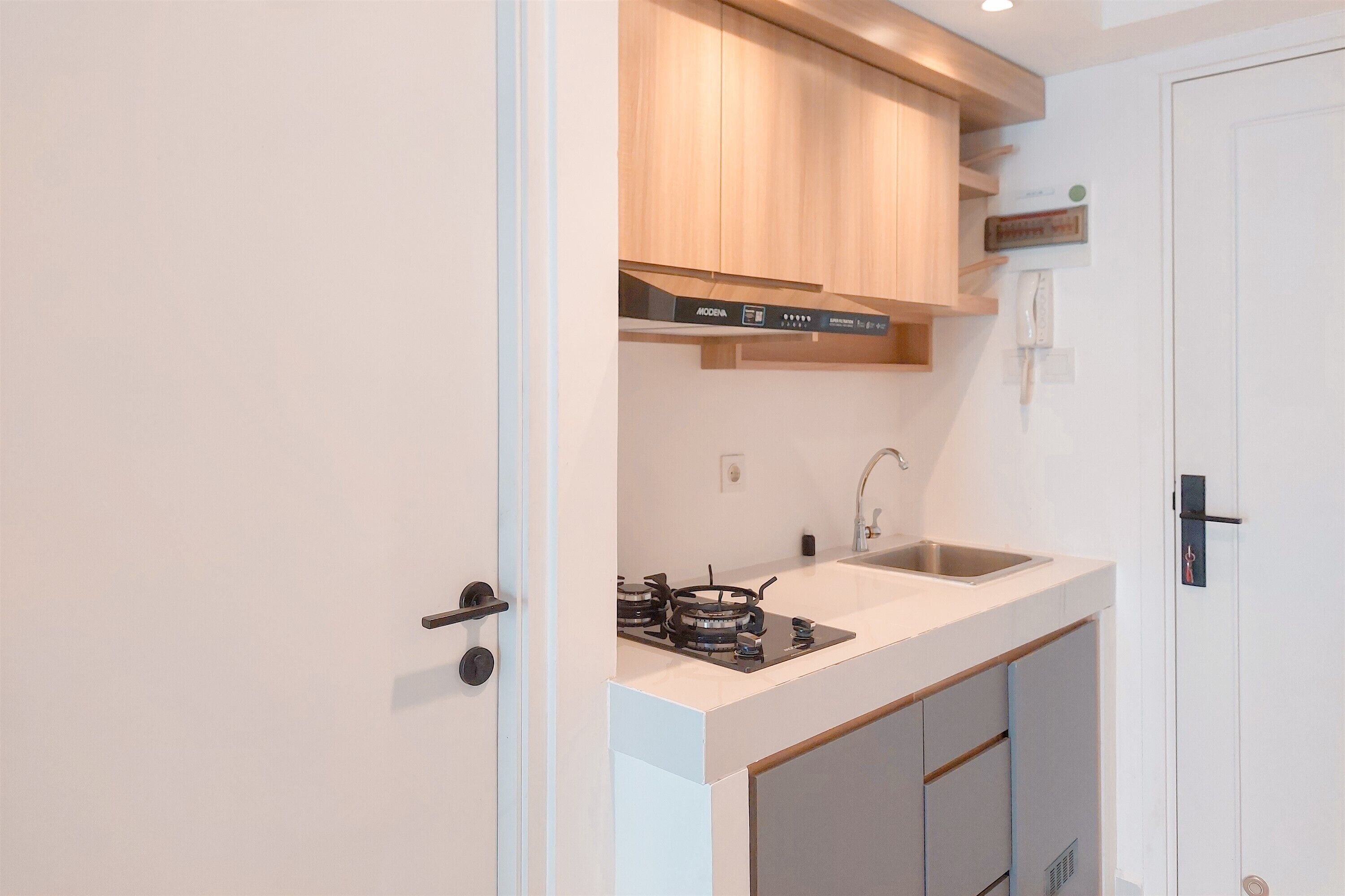 A compact kitchen with a gas stove, a sink, and wooden cabinets.