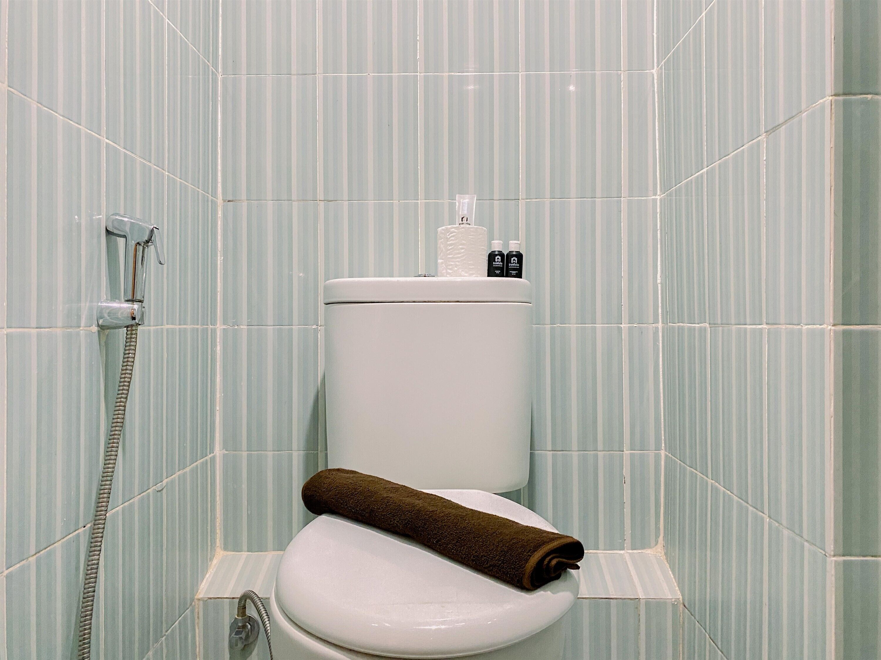A bathroom with a toilet, a shower, and a towel on the seat.