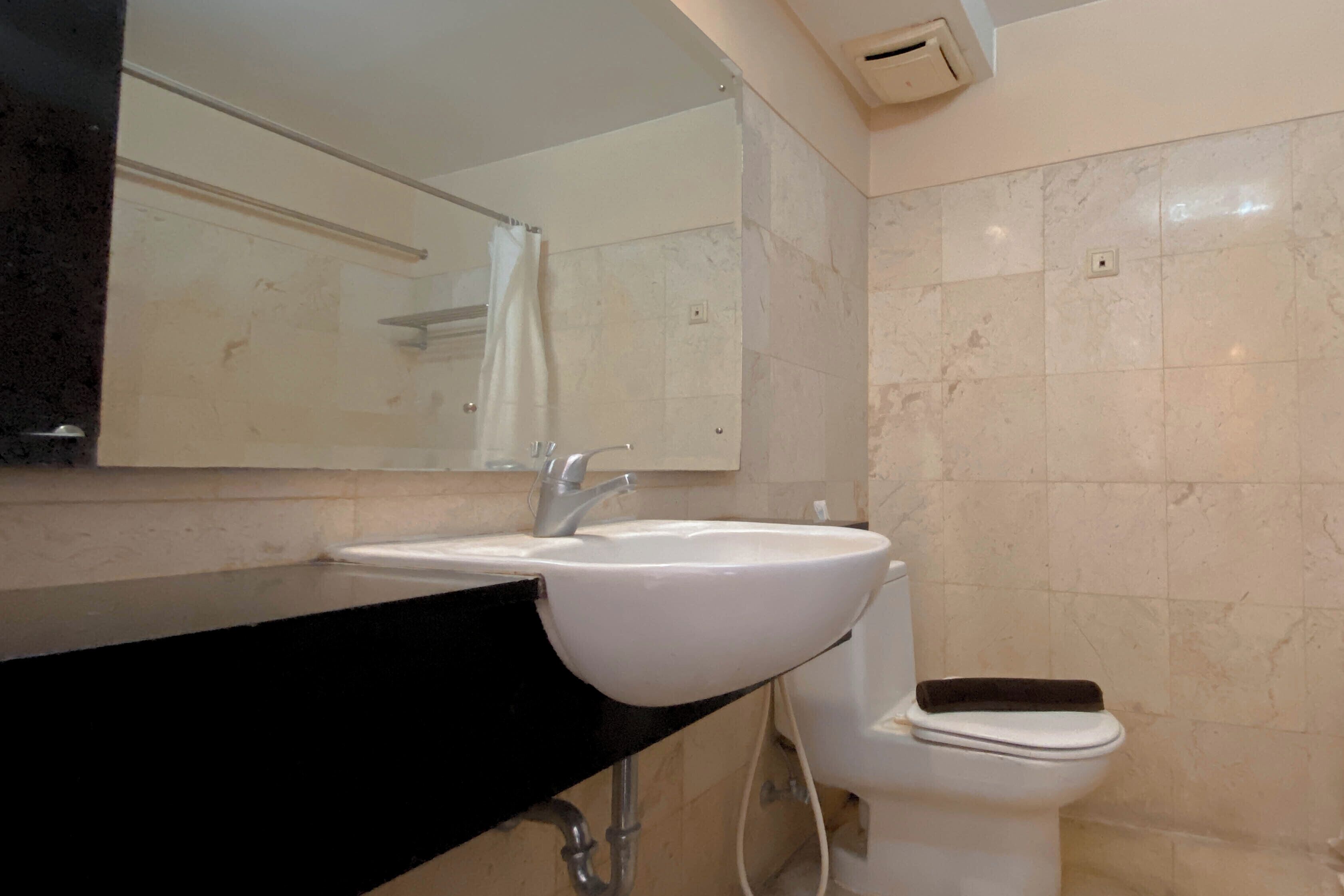 A bathroom with a white sink, a mirror, and a toilet.
