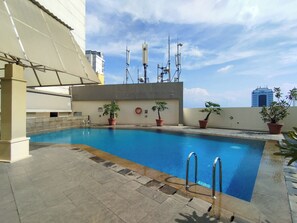 A rooftop pool with potted plants and a view of the city skyline. - Clean 2Br At Braga City Walk Apartment (Bandung)
