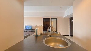 A modern bathroom with a sink, mirror, and a kettle. - Clean 2Br At Braga City Walk Apartment (Bandung)