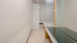 A narrow hallway with a glass partition on one side and a white door at the end. - The Cozy Cranny 2Br At Galeri Ciumbuleuit 1 Apartment (Bandung)