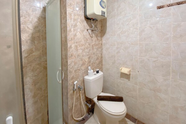A bathroom with a toilet, a shower, and a hand dryer.