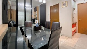 A modern dining area with a glass table, leather chairs, and pendant lighting. - The Cozy Cranny 2Br At Galeri Ciumbuleuit 1 Apartment (Bandung)