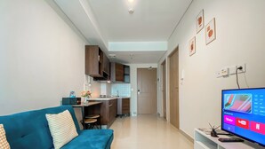 A modern living room with a blue sofa, a TV on a stand, and a kitchen in the background.