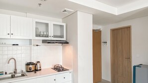 A compact kitchen with white cabinets, a stainless steel sink, a gas stove, and a built-in oven.