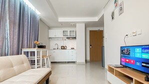 A modern living room with a sofa, a TV, and a kitchen in the background.