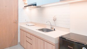 A modern kitchen with a stainless steel sink, wooden cabinets, and a black dishwasher. - Good Place And Relaxing Studio Apartment At B Residence (Pagedangan)