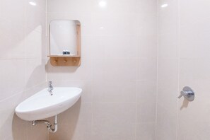 A bathroom with a white sink, a mirror, and a towel rack. - Good Place And Relaxing Studio Apartment At B Residence (Pagedangan)