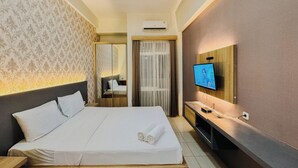 Una camera d'albergo con un letto grande, una televisione montata a parete e uno specchio sopra il letto.