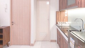 Cocina con armarios de madera, una puerta blanca y un lavamanos de acero inoxidable.