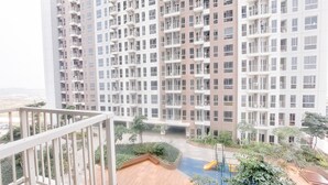 Un edificio residencial de gran altura con varios balcones y un patio ajardinado con una piscina pequeña y un tobogán.