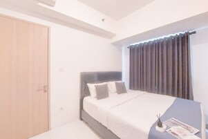 Un dormitorio con una cama, una puerta de madera y una ventana con cortinas.