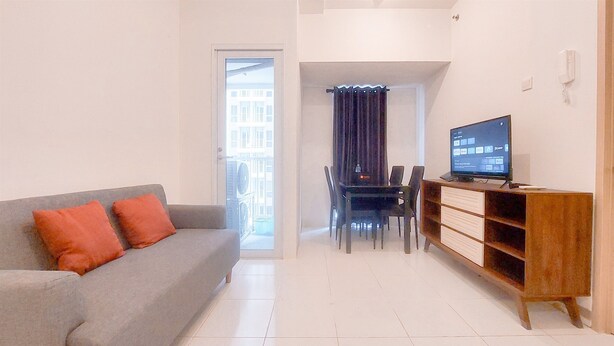 Una sala de estar con un sofá gris, un mueble de televisión de madera y una zona de comedor con mesa y sillas.
