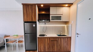 A compact kitchenette with a built-in refrigerator, microwave, and sink. - Good Deal And Restful 1Br Apartment Tamansari Skylounge Makassar (Makassar)