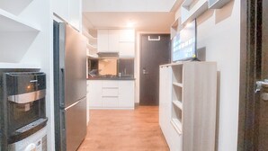 A narrow kitchen with stainless steel appliances, white cabinetry, and a wooden floor. - Good And Modern 2Br At Citra Living Apartment (Jakarta)
