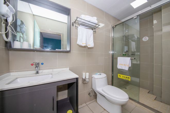 A bathroom with a sink, mirror, toilet, and glass shower enclosure.