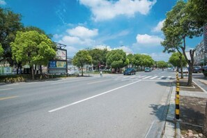 Uma rua larga, arborizada e com céu claro.