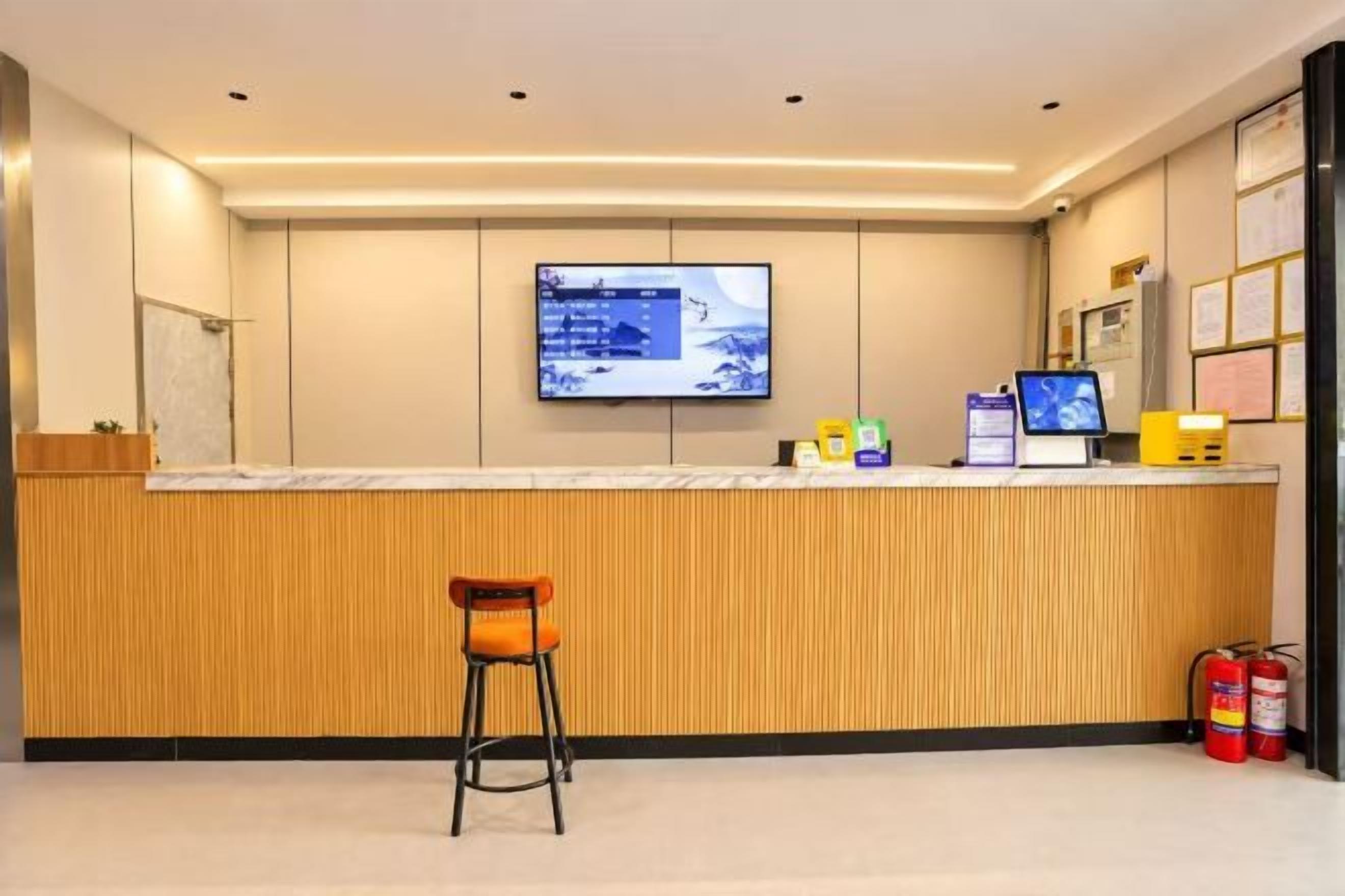 Una zona de recepción con un mostrador de madera, un monitor de computadora, un extintor y una manguera contra incendios.