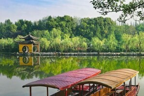Um lago calmo com um pavilhão tradicional e um barco.