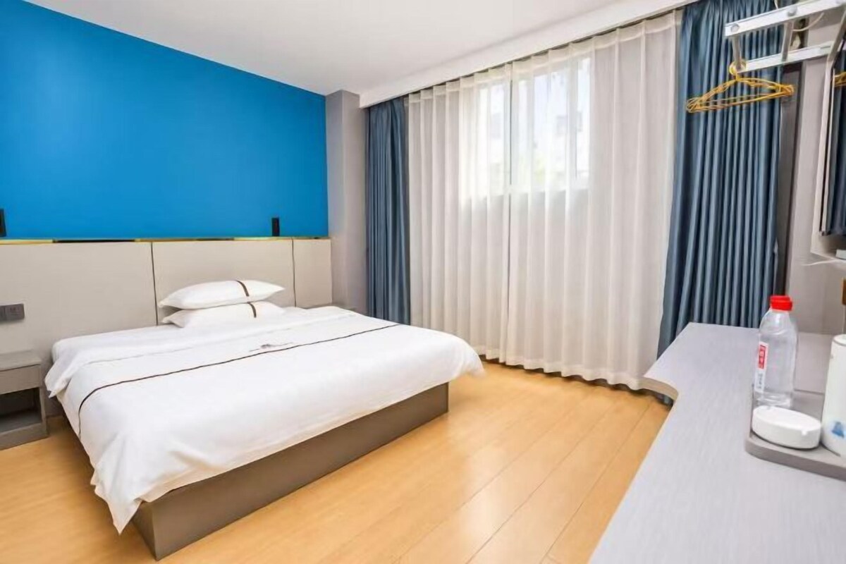 Ein Hotelzimmer mit Bett, Nachttisch und einem fenster mit Vorhängen.