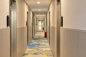 A hotel hallway with doors on both sides, a patterned carpet, and a red trash bin in the center. - Yuexuan lan Hotel (Yangzhou Slender West Lake) (Yangzhou)