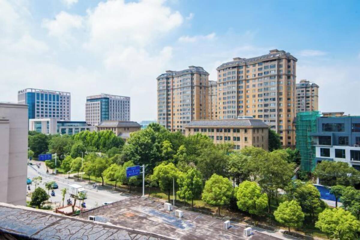 A high-rise building complex with multiple floors, surrounded by greenery and a clear sky.