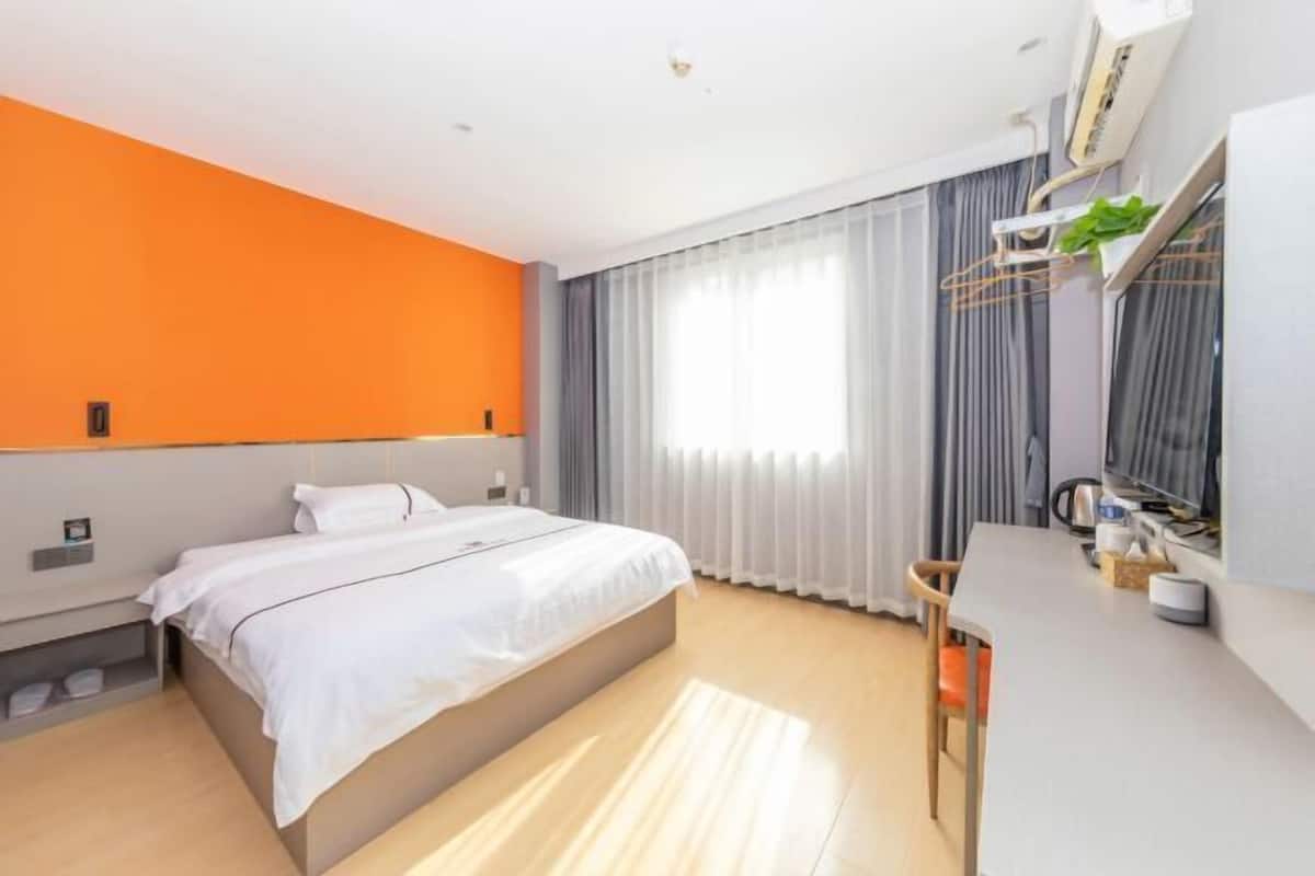 Ett modernt hotellrum med en stor säng, ett skrivbord och ett fönster med gardiner.