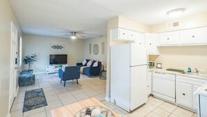 Ein kompakter Wohnraum mit Küche, Essbereich und einer Sitzecke mit Sofa und Fernseher.