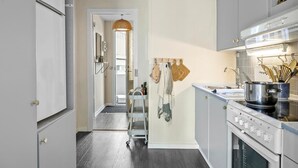 Une cuisine moderne équipée d’un four encastré, d’un évier et d’une cuisinière. Une échelle en bois mène à une mezzanine.