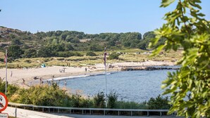 Une plage avec des gens, un drapeau et un ciel dégagé.