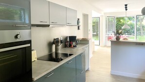A modern kitchen with a built-in oven, a coffee machine, and a window overlooking a garden.