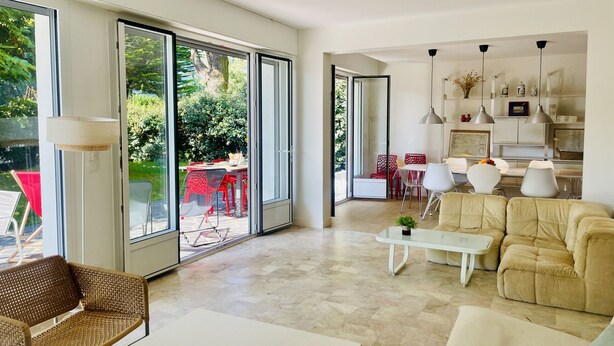 A modern living room with a sofa, coffee table, and a dining area with chairs.