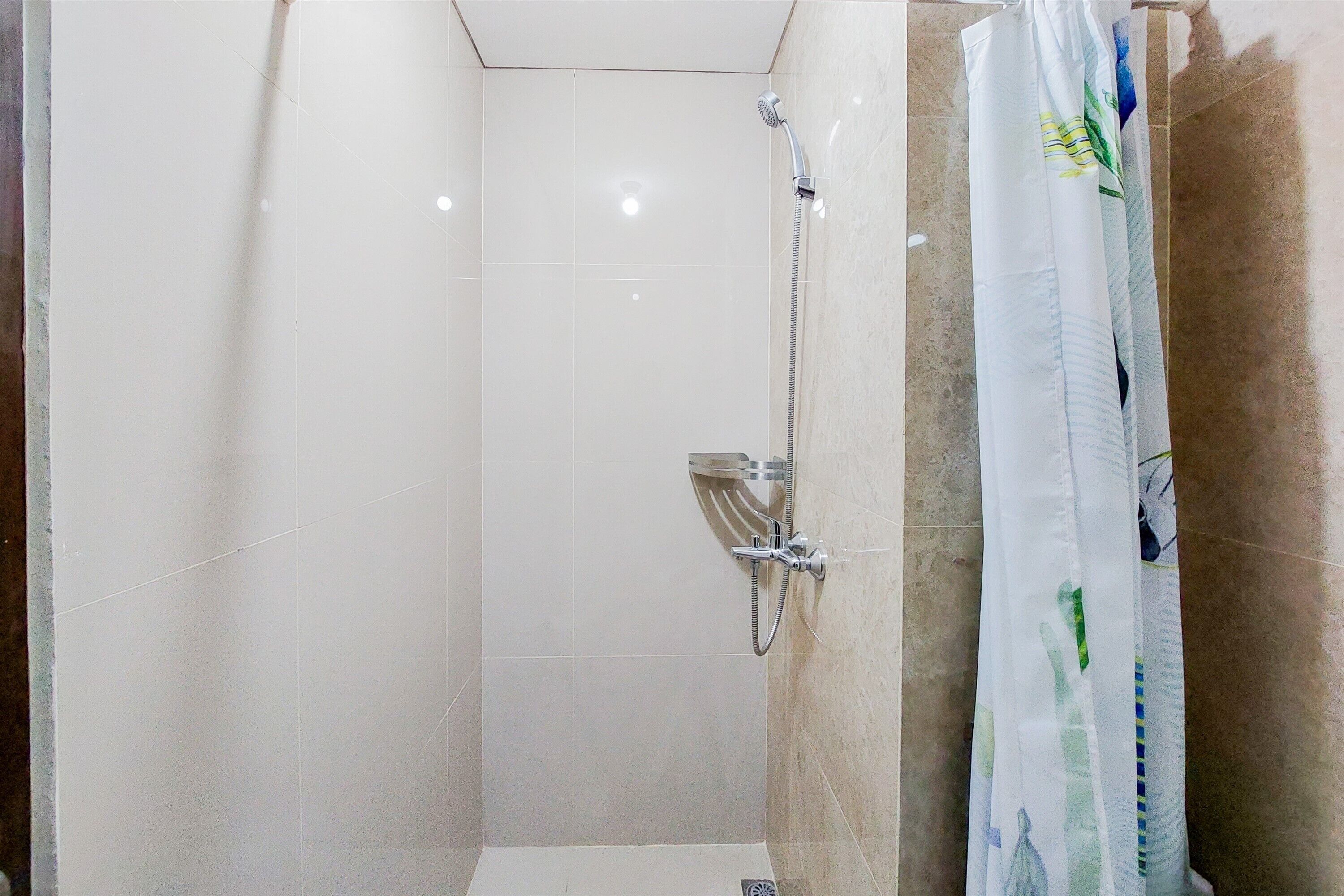 A small, tiled shower area with a handheld showerhead and a wall-mounted faucet.