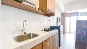 Una cucina moderna con piastrelle bianche, lavello in acciaio inossidabile, pensili in legno e piano cottura integrato.