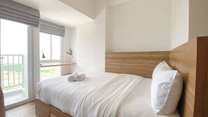 Una camera da letto con una testiera in legno, un'ampia finestra vista panoramica e un letto rifatto con asciugamani.