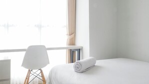 A hotel room with a bed, a chair, and a window with curtains. - Exquisite And Vibrant 2Br Apartment At Taman Melati Surabaya (Surabaya)