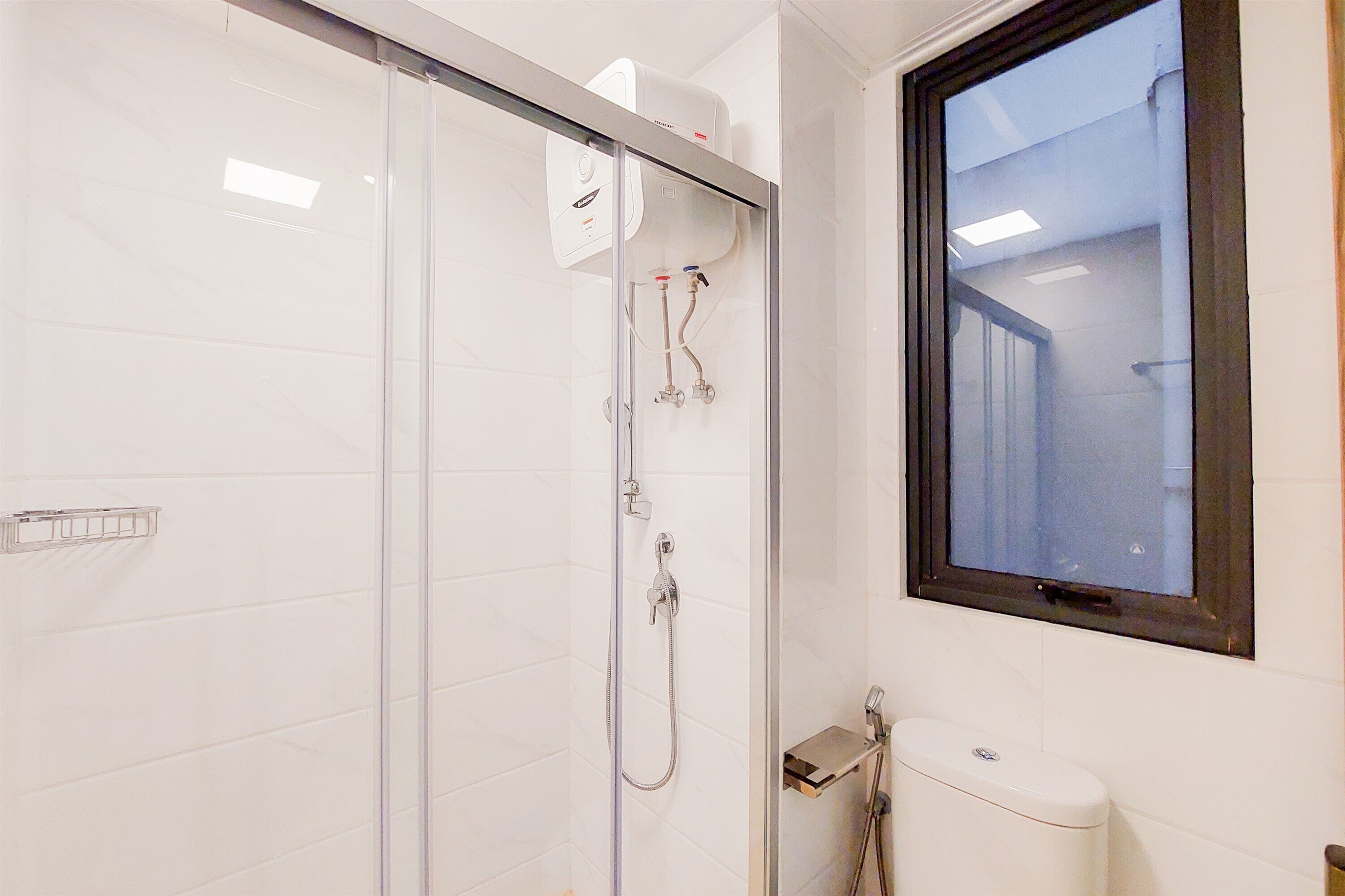 A modern bathroom with a glass shower enclosure, a toilet, and a window.