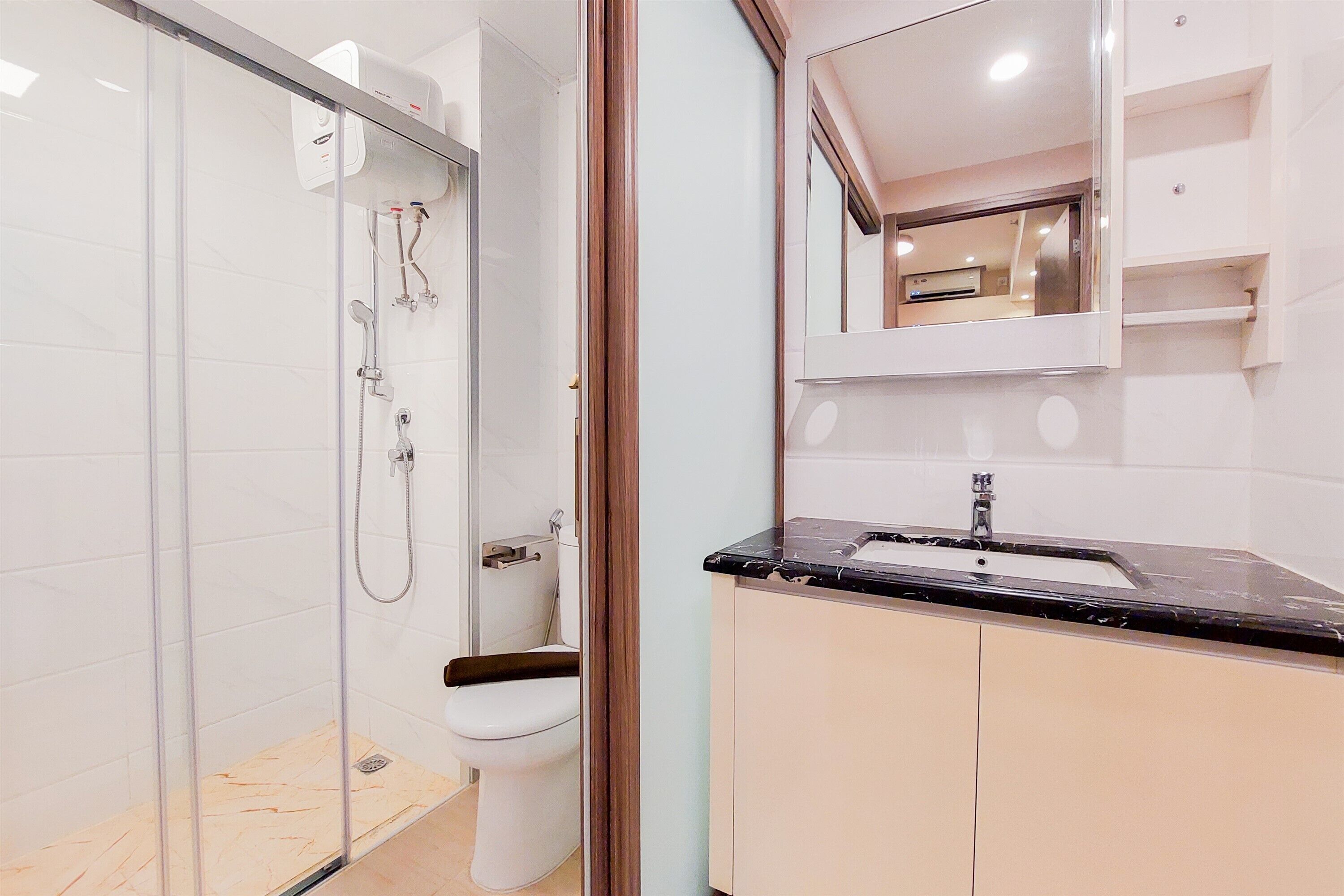A modern bathroom with a glass-enclosed shower, a toilet, and a vanity with a sink and mirror.