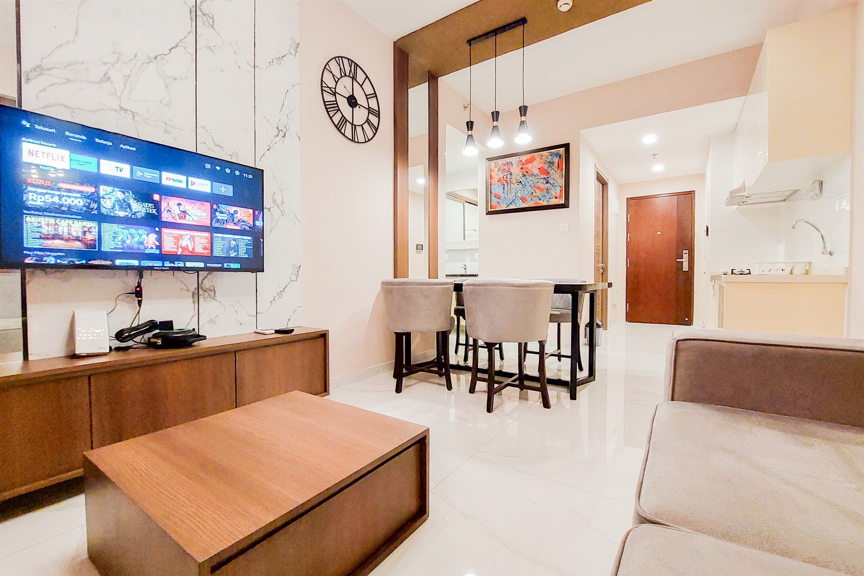A modern living room with a flat-screen TV, a wooden coffee table, and a seating area.