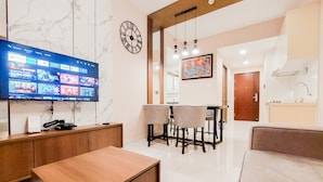 A modern living room with a flat-screen TV, a wooden coffee table, and a seating area. - Modern And Nice 2Br At 30Th Floor Sky House Bsd Apartment (Pagedangan)