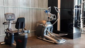 A gym with cardio machines, including a treadmill and an elliptical. - Cozy Studio At Brooklyn Alam Sutera Apartment (South Tangerang)
