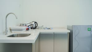 A modern kitchen with a stainless steel sink, a kettle, and a refrigerator. - Cozy Studio At Brooklyn Alam Sutera Apartment (South Tangerang)