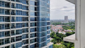 A high-rise building with multiple floors, large windows, and a view of a cityscape in the background. - Cozy Studio At Brooklyn Alam Sutera Apartment (South Tangerang)