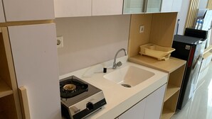 A compact kitchen with a white countertop, a sink, and a gas stove. - Cozy Nice Studio At Signature Park Grande Apartment (Jakarta)