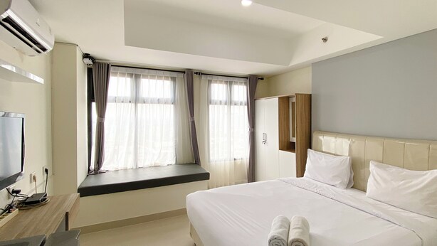 Una habitación de hotel con cama, televisor, ventana con cortinas y armario.