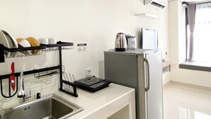 Cocina compacta con pileta, escurreplatos, tetera, tostadora y refrigerador.