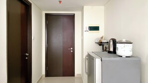 Un pasillo con una puerta cerrada, un refrigerador y un microondas sobre una encimera.