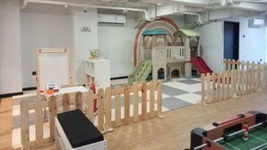 A children's play area with a slide, climbing structures, and a small table with toys.